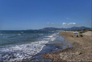 a beach with people sitting under an umbrella and the ocean at Apartamento en playa de Torrenostra in Torrenostra