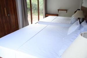 two white beds in a room with a window at Visit Wilpattu in Pahala Maragahawewa