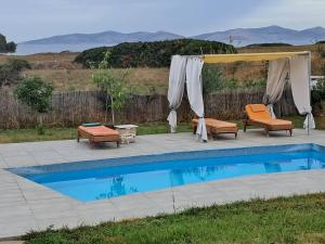 een zwembad met een prieel en stoelen naast bij Kenny's Villa in Mastichari