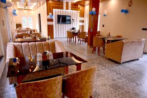 a dining room with couches and tables and chairs at Hotel Highway Nest in Chamba