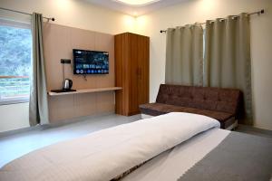 a bedroom with a bed and a couch and a television at Hotel Highway Nest in Chamba +9 photos