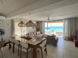 a dining room and living room with a table and chairs at Turquoise Bay Beach Apartments Trou d'Eau Douce in Trou d'Eau Douce