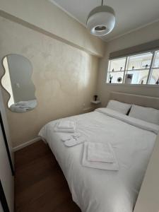 una camera da letto con un letto bianco con asciugamani sopra di BK Urban Living a Kateríni