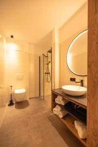 een badkamer met een wastafel, een toilet en een spiegel bij dein Dahoam Boutique Appartements in Gröbming +17 foto's