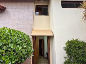 a door to a house with a large green bush at Villa Ipe in Patos de Minas