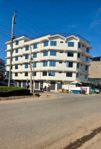 a large white apartment building on the side of a street at Rees haven in Nanyuki