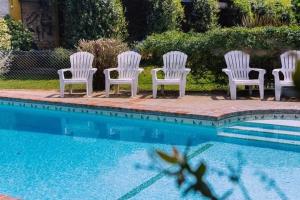 four white chairs sitting next to a swimming pool at Hostería Casa de Campo in Chascomús