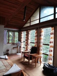 a living room with windows and a chair and a table at Munnar Tree house and Farm in Munnar