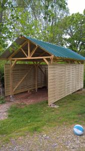 a wooden shed with a roof and a frisbee in the grass at Gîte A l'orée des bois in Saint-Robert