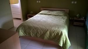a bedroom with a bed with a green comforter at Gîte A l'orée des bois in Saint-Robert