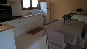 a kitchen with a table and a white refrigerator at Gîte A l'orée des bois in Saint-Robert +2 photos