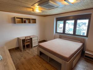 a bedroom with a bed and a desk and windows at Apartmán Horal in Jilemnice