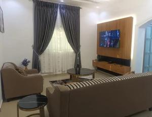 a living room with a couch and a tv at Travel Lodge Apartment in Sagisa