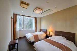 a hotel room with two beds and a window at Shiki Resorts Kusatsu Saisonnier in Kusatsu