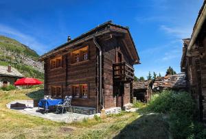 a wooden house with a blue table in front of it at Chalet Tuk-Tuk in Zermatt