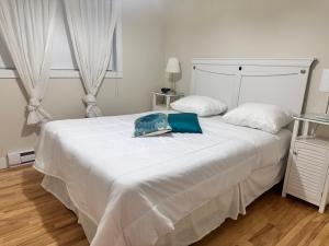 un letto bianco con due cuscini sopra di Appartement meublé 2ch - Verone 6 a Laval
