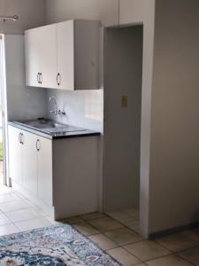 a kitchen with white cabinets and a sink at 899 On Burlington in Pretoria