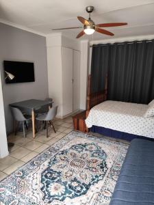 a bedroom with a bed and a table and a ceiling fan at 899 On Burlington in Pretoria +9 photos