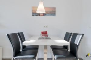 a white dining room table with black chairs and a glass bowl on it at Villa Marin, Wohnung 16 in Zinnowitz +28 photos