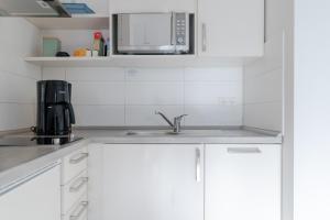 a white kitchen with a sink and a microwave at Villa Marin, Wohnung 16 in Zinnowitz