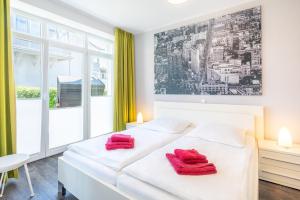 een witte slaapkamer met 2 rode handdoeken op een bed bij Villa Marin Wohnung 04 in Zinnowitz