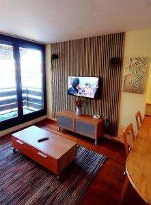 un soggiorno con un tavolo e una tv di Refuge du Renard au Bord du Lac a Malbuisson