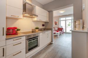 a kitchen with white cabinets and a red appliance at Villa Marin, Wohnung 14 in Zinnowitz