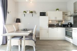 a kitchen with white cabinets and a table and chairs at Villa Marin, Wohnung 17 in Zinnowitz