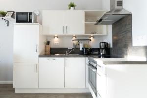 a white kitchen with white cabinets and a sink at Villa Marin, Wohnung 17 in Zinnowitz