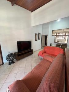 a living room with a red couch and a flat screen tv at Casa Fácil in Itacaré