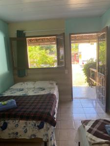 a bedroom with a bed and two windows and a porch at Pousada Encantos de Paripueira in Paripueira