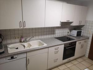 a kitchen with white cabinets and a sink and a microwave at Ferienwohnung Kulla in Albstadt