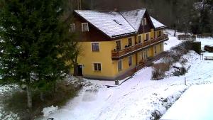 a yellow house in the snow with snow covered ground at Pension Ostrauer Mühle in Bad Schandau