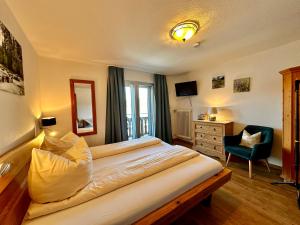 a bedroom with a large bed and a chair at Hotel Fischerstüberl am See in Tegernsee