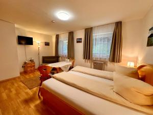 a hotel room with two beds and a chair at Hotel Fischerstüberl am See in Tegernsee