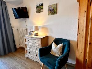 a room with a chair and a dresser with a television at Hotel Fischerstüberl am See in Tegernsee +3 photos