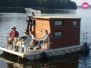 a group of people sitting on a house boat in the water at Kleines Hausboot - ideal für Ihren Angelurlaub! in Lychen