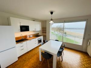 a kitchen with white cabinets and a table and a window at Apartment with exceptional views in Saint-Nazaire