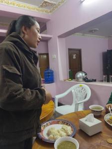 Una donna in piedi a un tavolo con un piatto di cibo di Annapurna Himdrishya Pokhara a Pokhara