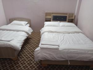 2 letti in una camera con lenzuola e cuscini bianchi di Annapurna Himdrishya Pokhara a Pokhara