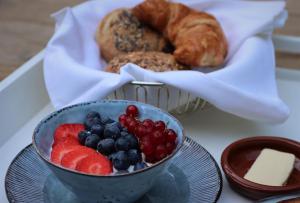 a bowl of fruit and a basket of bread and pastries at Forest Inn in Ugchelen