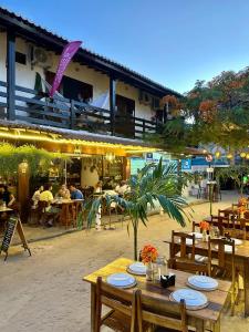 a restaurant with wooden tables and people sitting at tables at Flat dboa in Jericoacoara