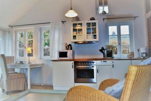 a kitchen with white cabinets and a stove top oven at Alte Fischerkate und Möwennest in Groß Zicker
