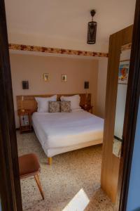 a bedroom with a white bed and a chair at Hôtel Restaurant Sole e Monte in Cuttoli-Corticchiato +17 photos