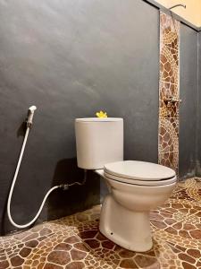 a bathroom with a toilet with a flower on the tank at Sudi Guest House in Pemuteran