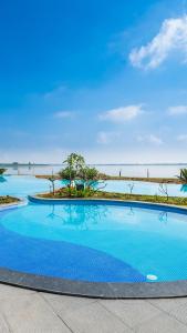 a blue swimming pool with the ocean in the background at Discovery Village Kabini in Antarasante