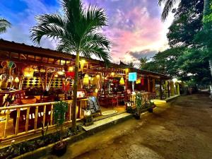 een restaurant met een palmboom ervoor bij Sunny Rose Bungalows Gili Air - Adults Only in Gili Air