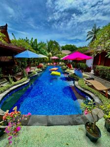 een zwembad in een resort met blauw water en parasols bij Sunny Rose Bungalows Gili Air - Adults Only in Gili Air