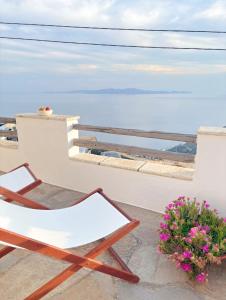 a chair on a balcony with a view of the ocean at Katastega Tinos in Istérnia