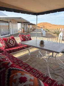 a table and chairs under an umbrella in the desert at Peaceful Luxury Camp in Merzouga